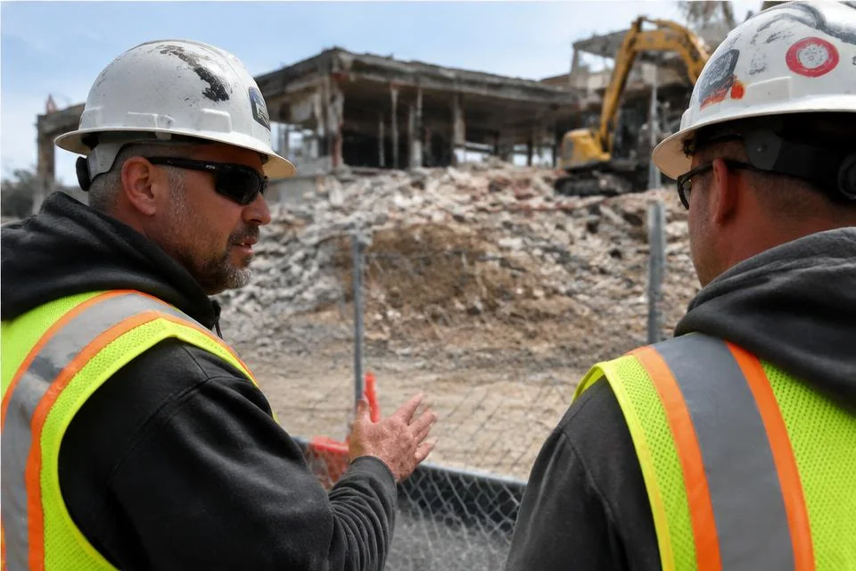 Workers in protective equipment reviewing a demolition worksite